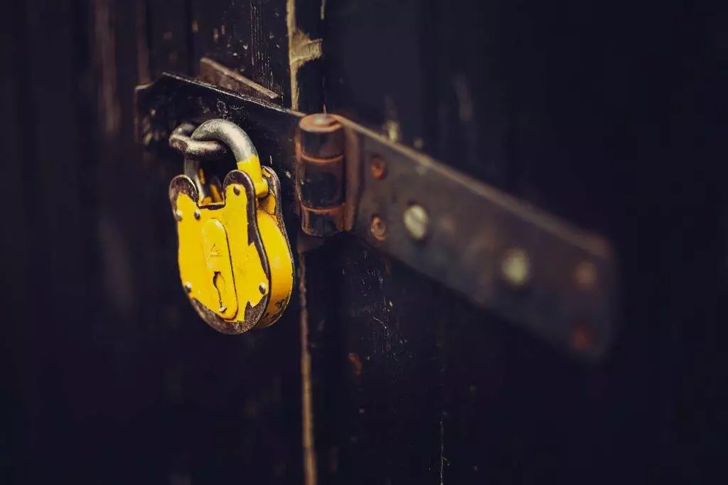 A yellow padlock on a wooden door.