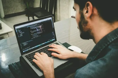A man working on a laptop with code on it.