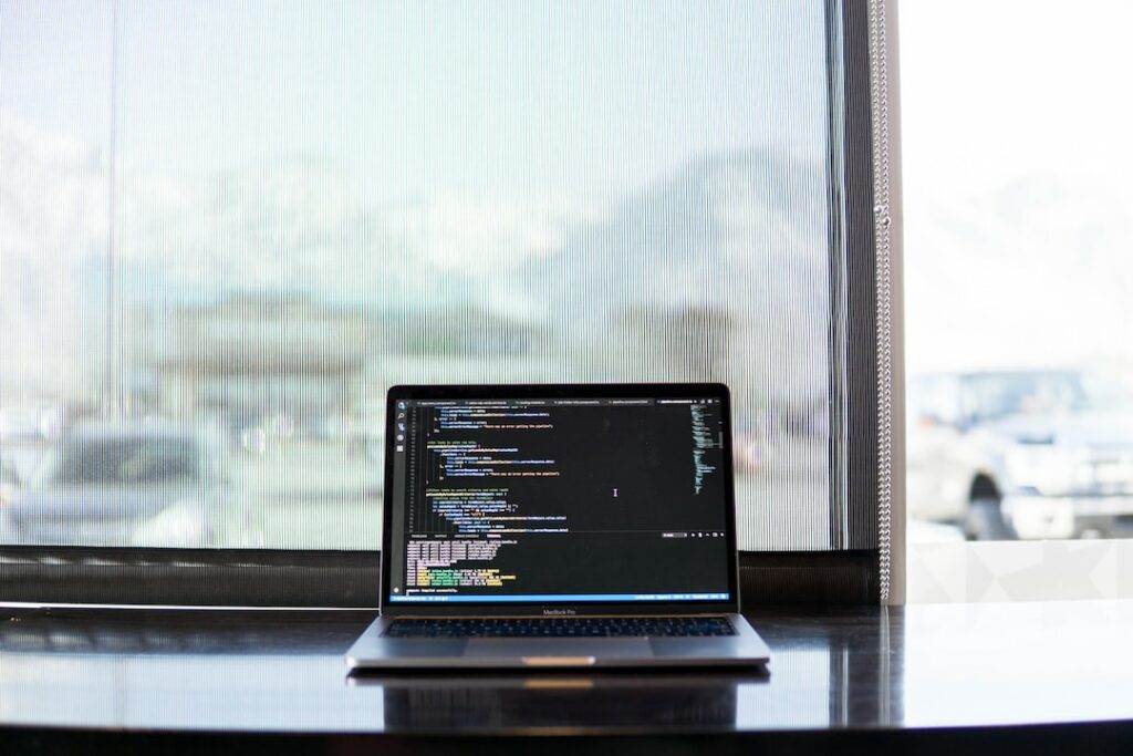 A laptop on a table in front of a window.