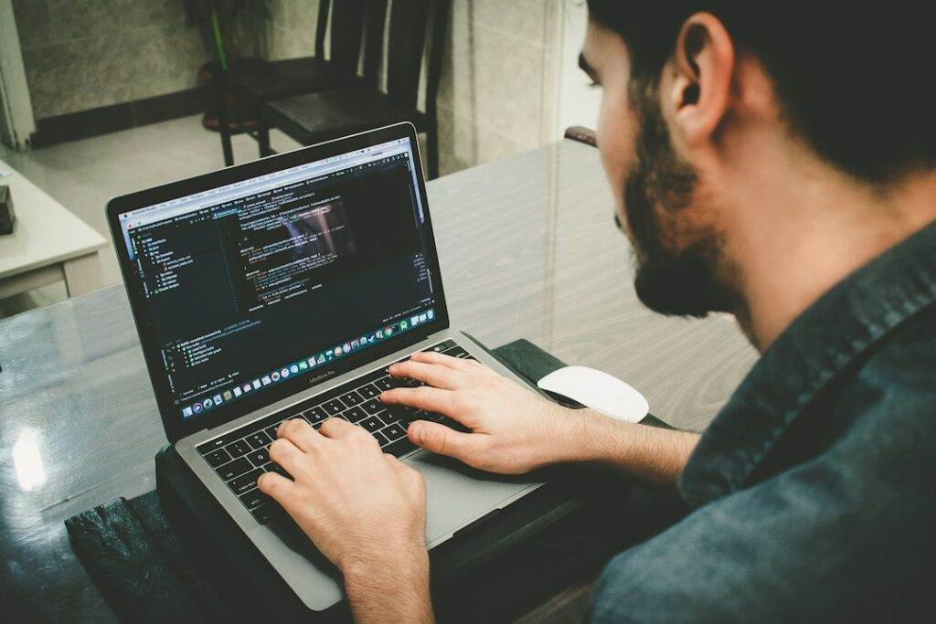 A man working on a laptop with code on it.