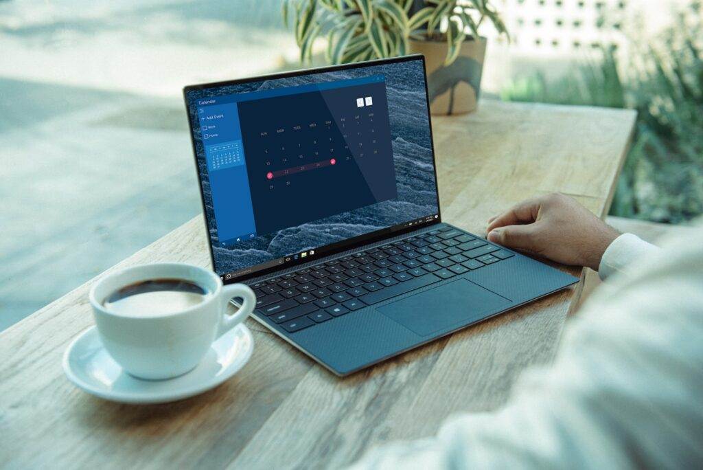 A man sitting at a table with a laptop and a cup of coffee.